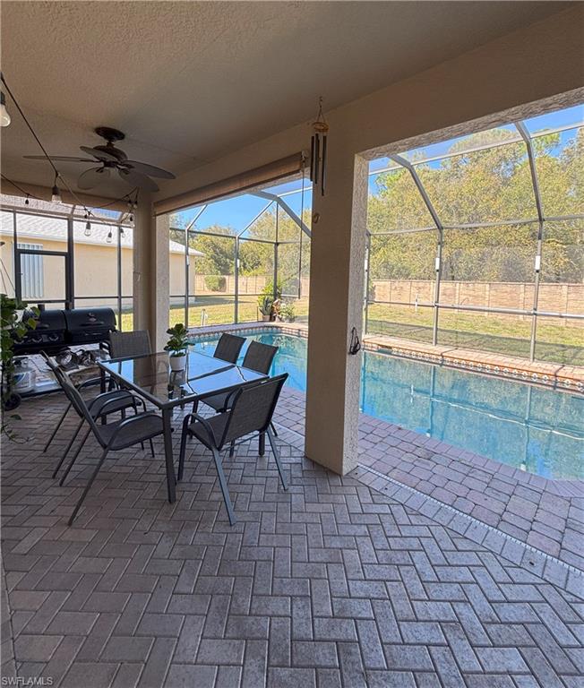 View of patio featuring a sunroom, glass enclosure, ceiling fan, and an outdoor pool