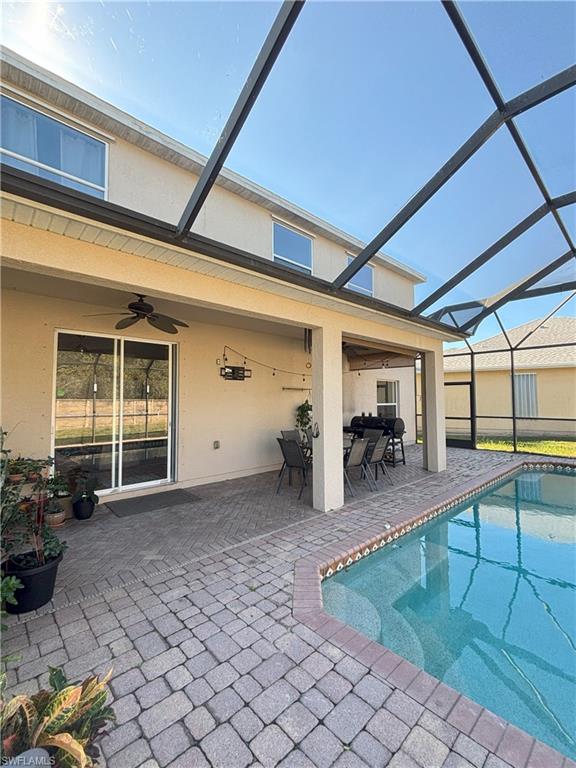 Outdoor pool with a sunroom, a patio area, and glass enclosure
