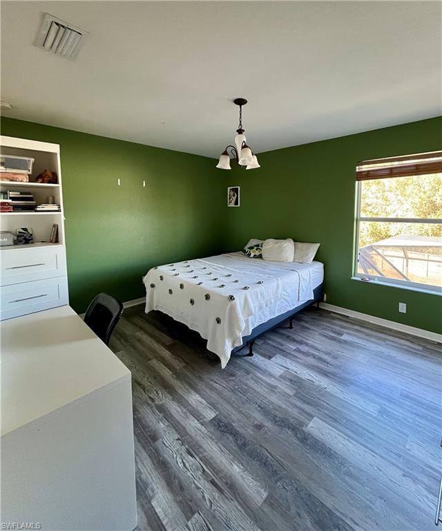 Bedroom with dark wood finished floors and baseboards