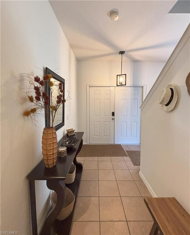Foyer entrance with light tile patterned floors and baseboards