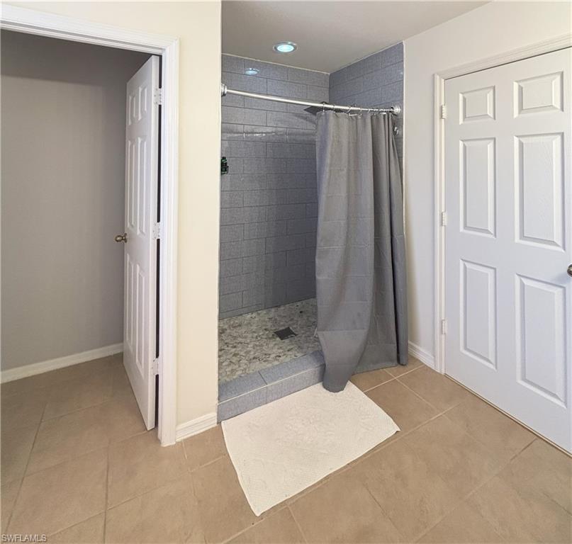 Full bathroom with light tile patterned floors, tiled shower, and recessed lighting