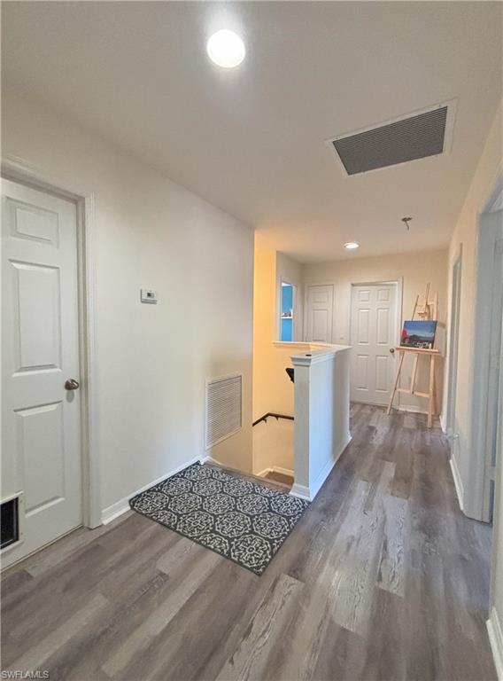 Hallway with an upstairs landing, recessed lighting, and dark wood-style flooring