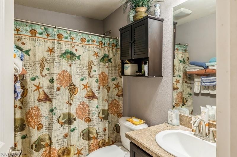 Full bathroom featuring a textured wall, vanity, and curtained shower