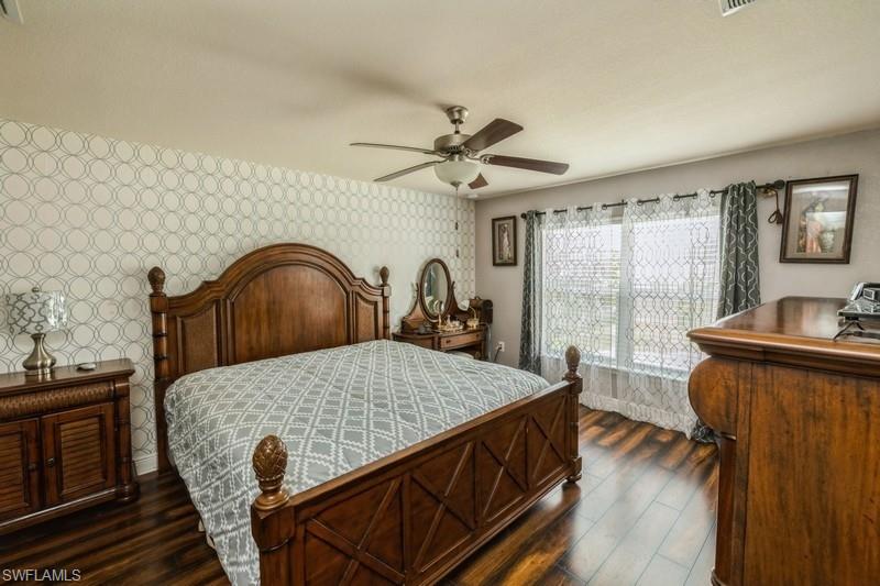 Bedroom featuring dark wood-style flooring, wallpapered walls, and a ceiling fan