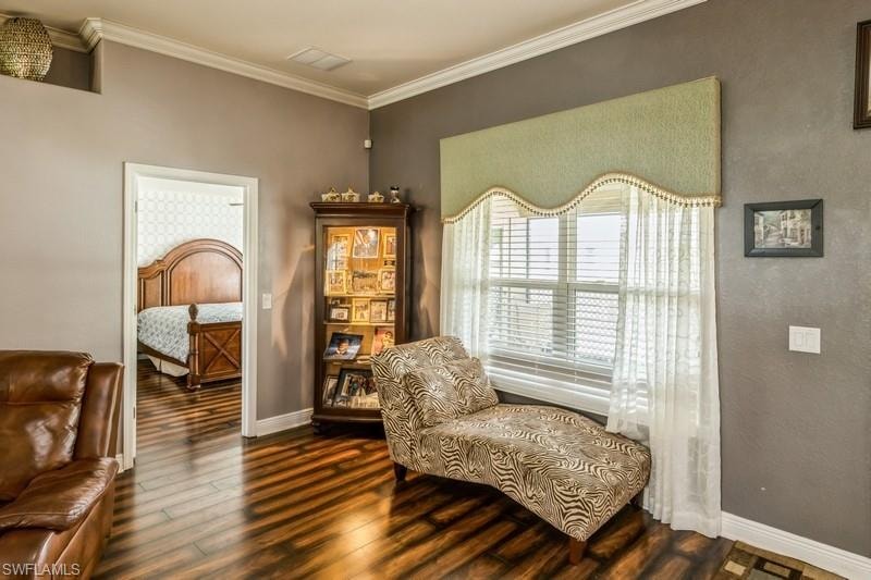 Living area with dark wood finished floors and crown molding