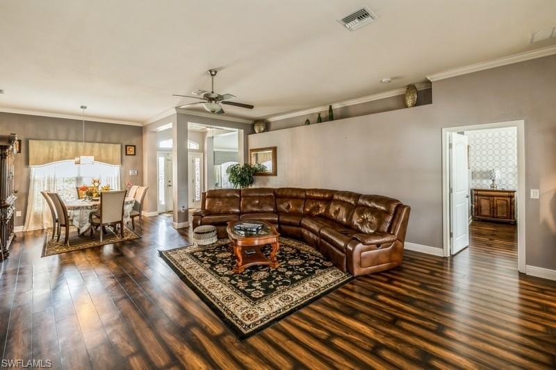 Living area featuring dark wood-type flooring, a ceiling fan, and crown molding
