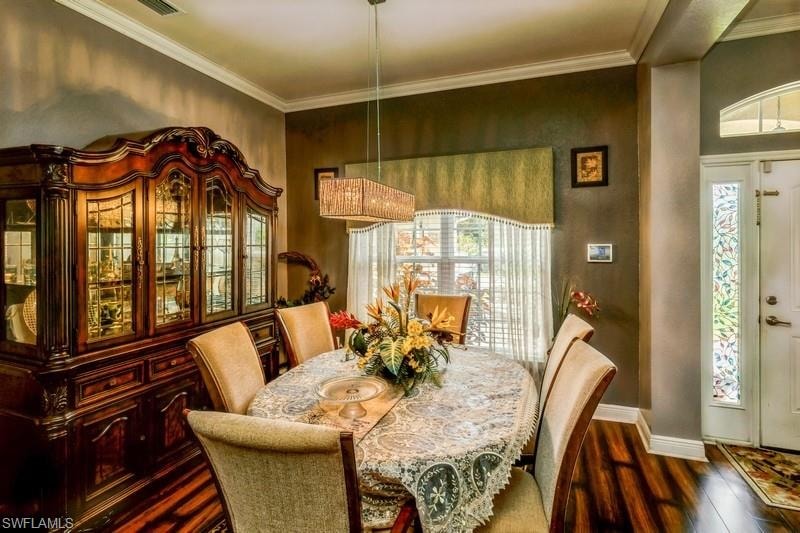Dining area featuring dark wood-style flooring and crown molding
