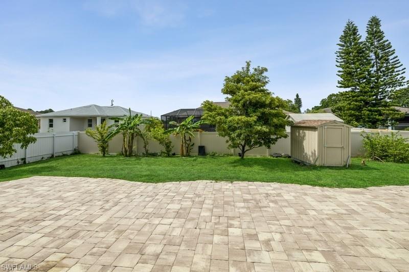 Fenced backyard featuring a shed