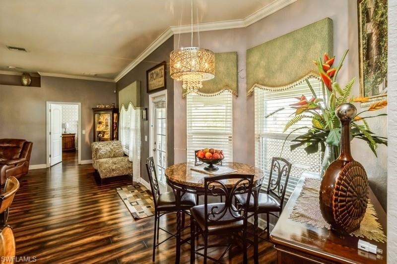 Dining room with ornamental molding, dark wood-style floors, and a chandelier