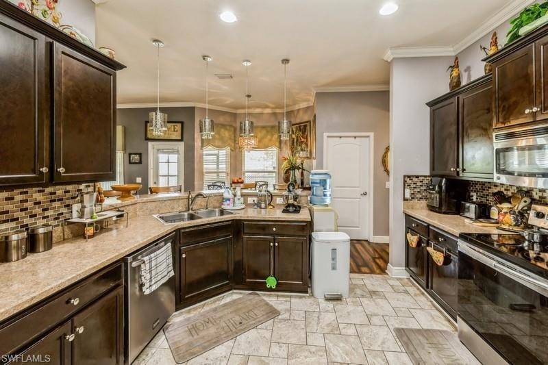 Kitchen featuring decorative backsplash, dark brown cabinetry, stainless steel appliances, a peninsula, and crown molding