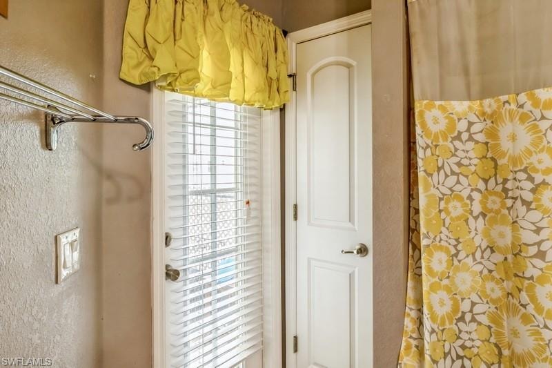 Full bath with a textured wall and a shower with shower curtain