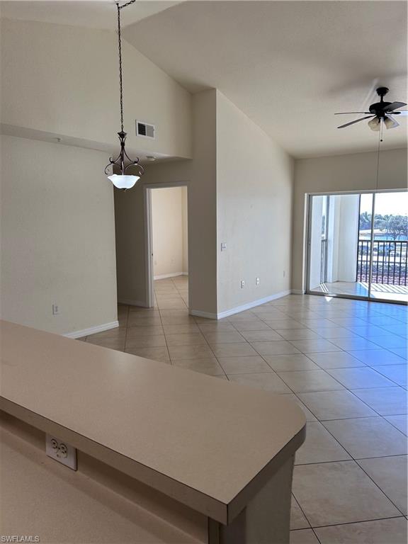 Unfurnished room with light tile patterned floors, lofted ceiling, and ceiling fan