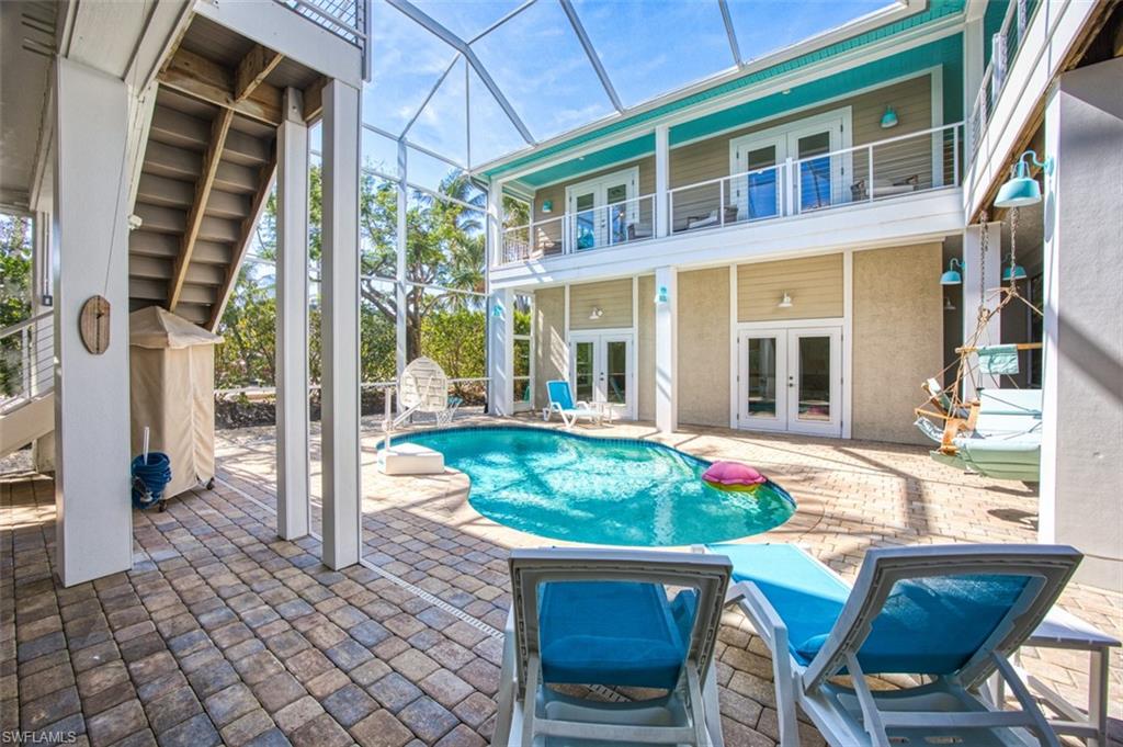 Swimming pool with a patio, a balcony, stairs, a lanai, and a wooden deck