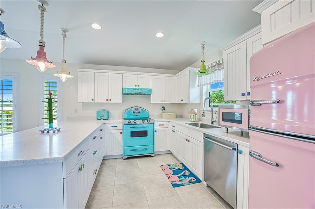 Kitchen featuring white cabinetry, a peninsula, appliances with stainless steel finishes, hanging light fixtures, and recessed lighting