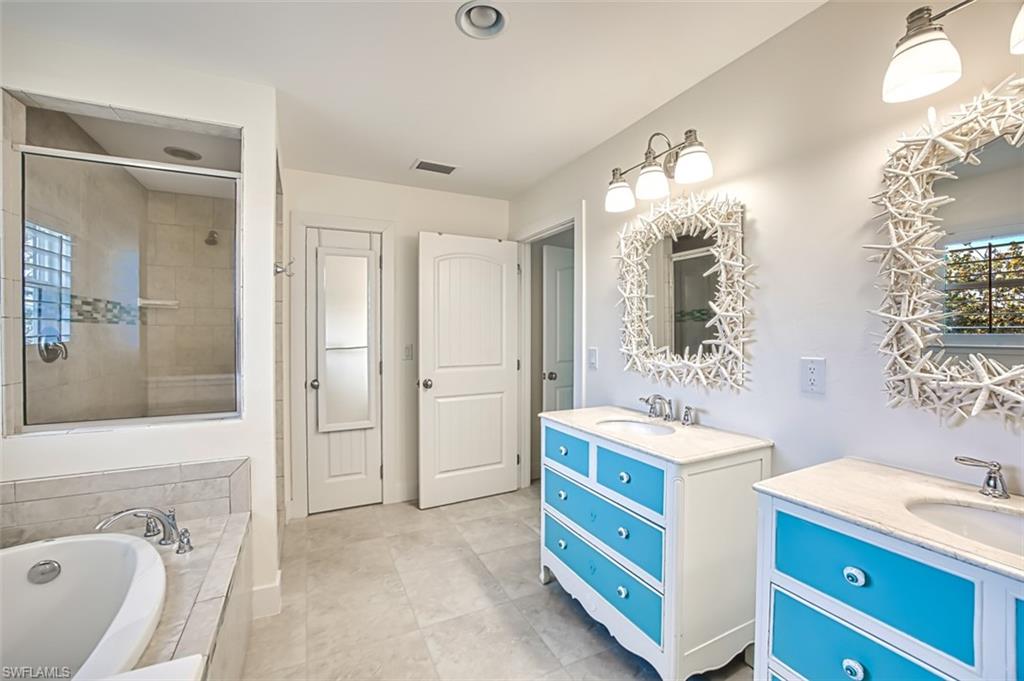 Bathroom with a bath, a stall shower, double vanity, recessed lighting, and light tile patterned floors
