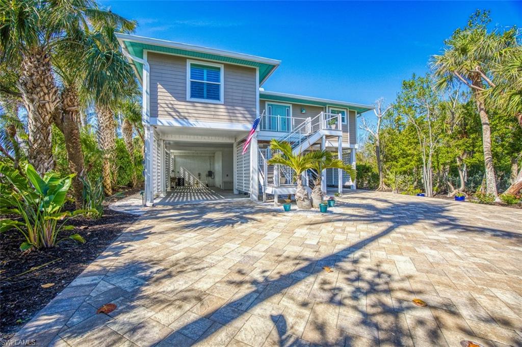 Coastal inspired home with a carport, stairway, decorative driveway, a deck, and a patio