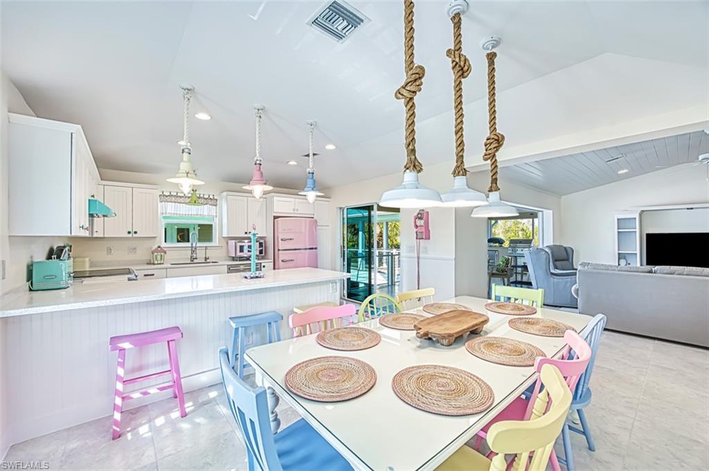 Dining area featuring light tile patterned floors, vaulted ceiling, and recessed lighting