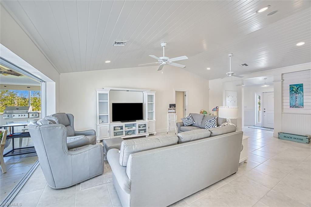 Living room with a ceiling fan, lofted ceiling, plenty of natural light, wood ceiling, and light tile patterned flooring