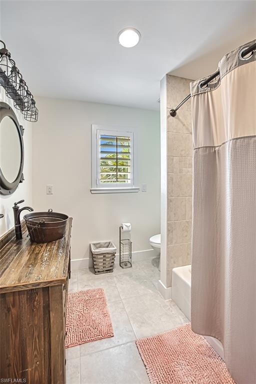 Full bath with vanity, shower / bath combo with shower curtain, and light tile patterned floors