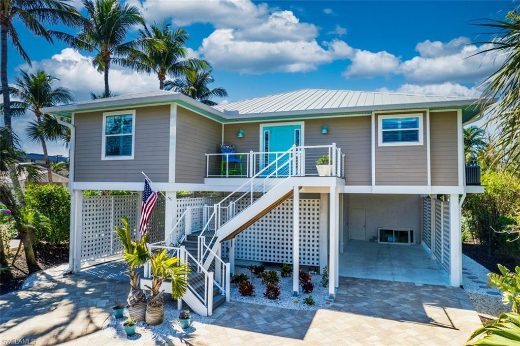 View of front of home featuring a carport, a patio, stairs, and a wooden deck