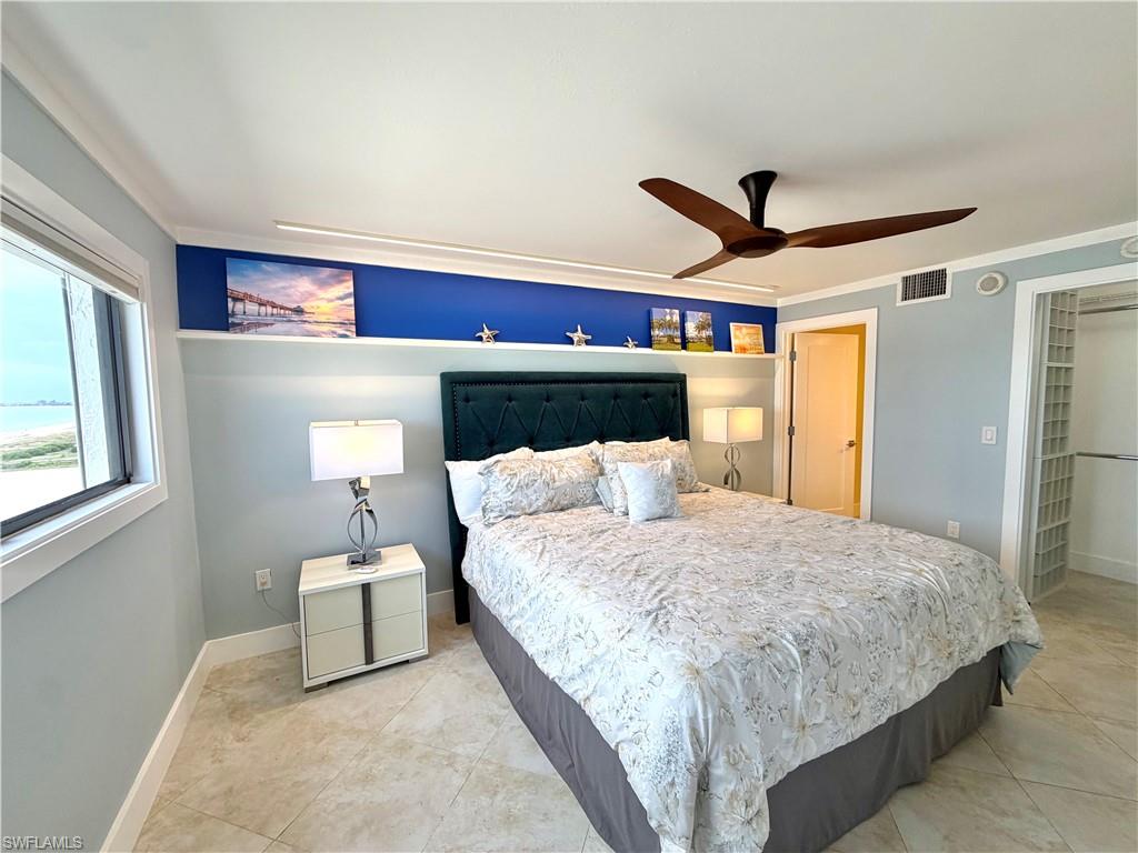 Screened balcony featuring a ceiling fan, tiled flooring, and a glass-paneled door