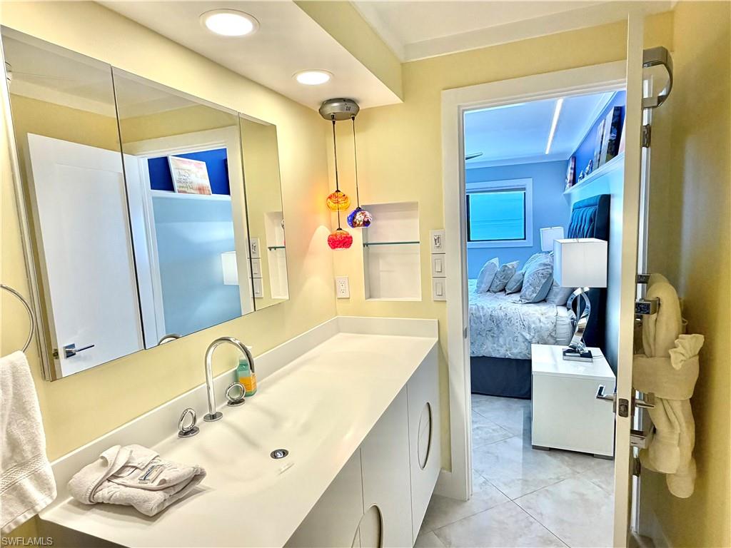Built-in white cabinetry with drawers and shelving, ceiling fan, window with exterior exposure, recessed ceiling lighting, and a tufted upholstered headboard