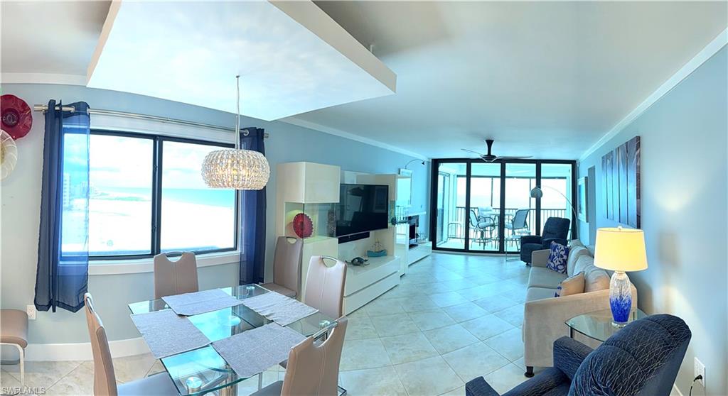 Open-concept living area with large windows, glass sliding doors, tile flooring, and a decorative ceiling fixture