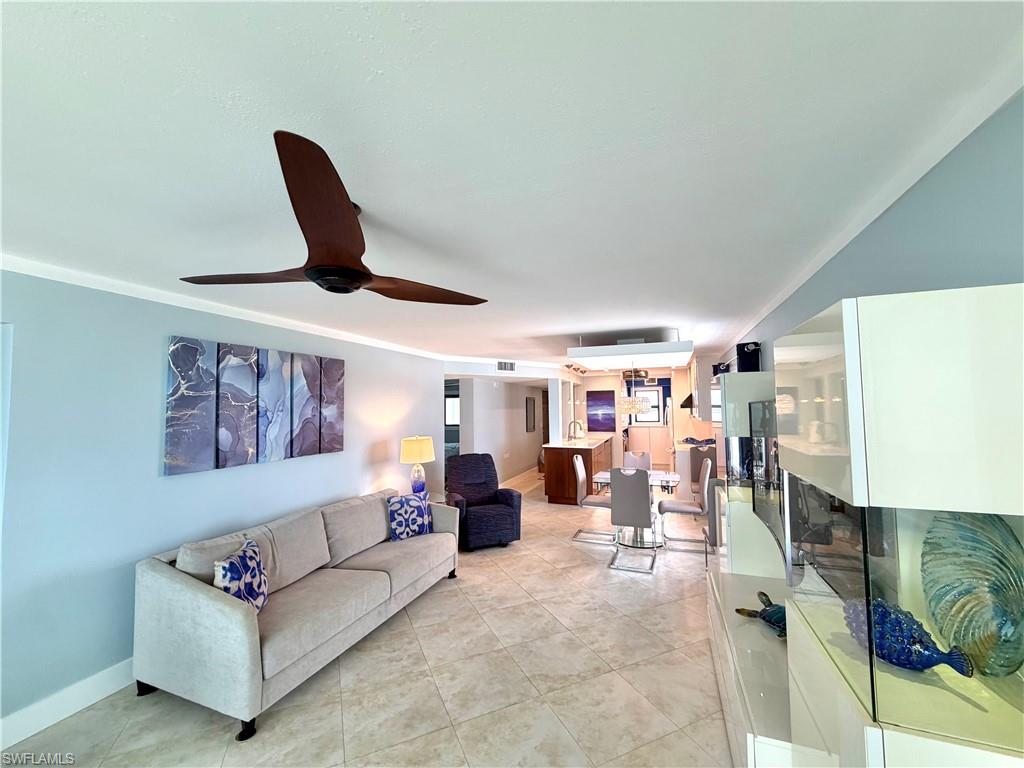 Contemporary kitchen featuring a large waterfall-edge island with wood-finish cabinetry, stainless steel appliances, quartz countertops, and tile flooring