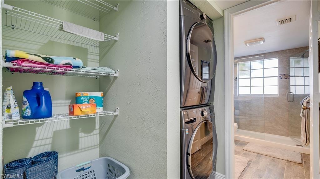 Laundry area with stacked washer and clothes dryer and a textured wall
