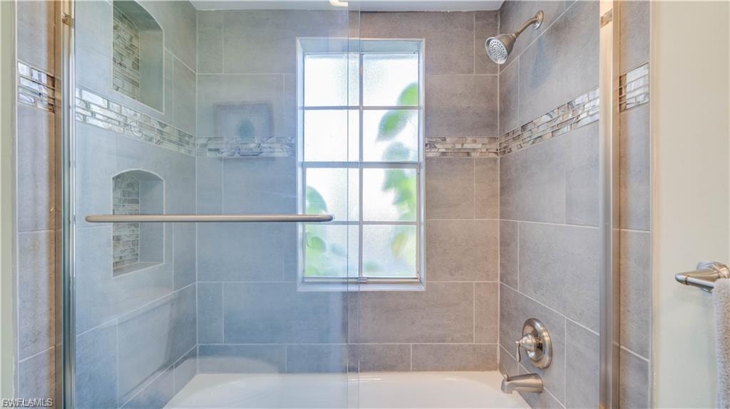 Bathroom with bath / shower combo with glass door