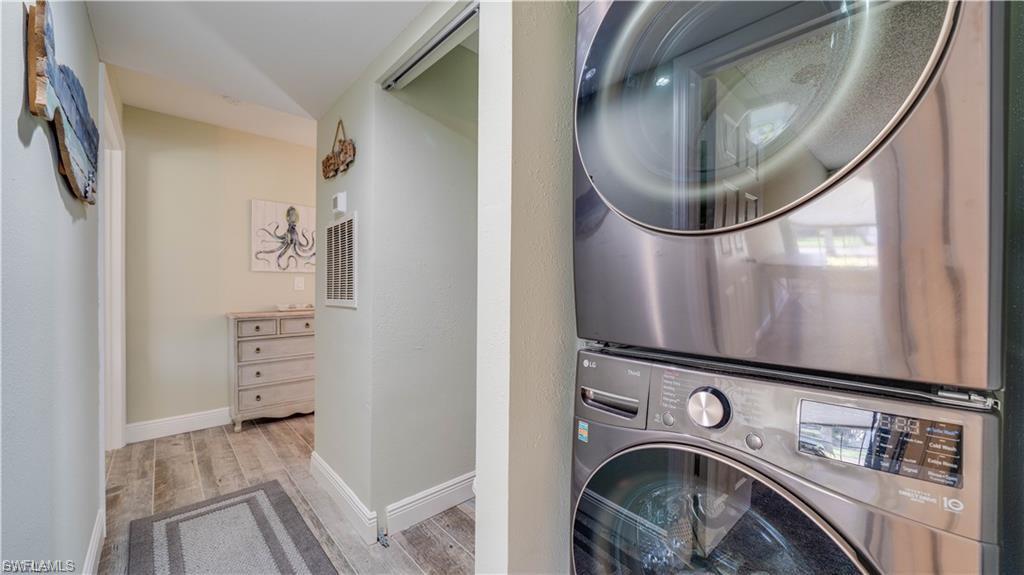Laundry area featuring stacked washing machine and dryer and light wood-style flooring