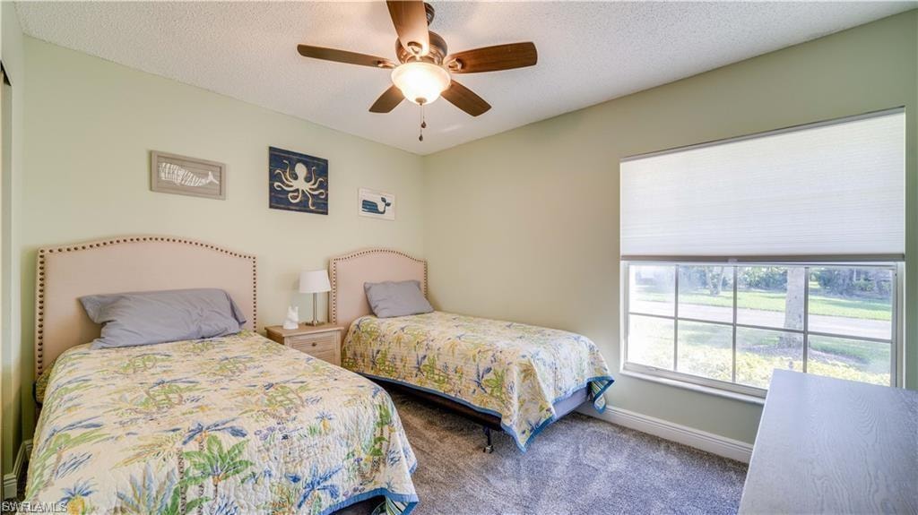 Carpeted bedroom featuring a textured ceiling and ceiling fan