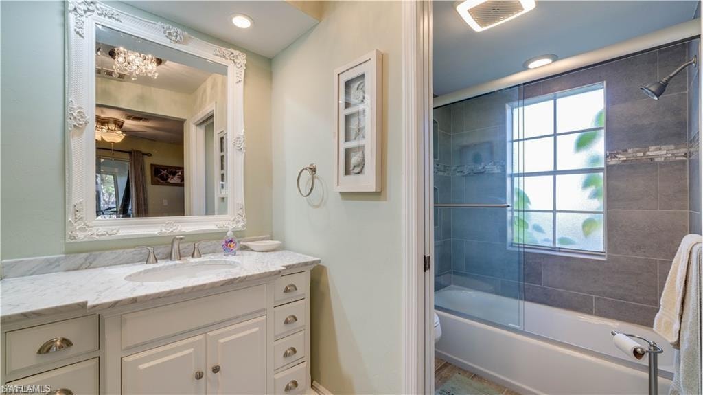 Bathroom with vanity and bath / shower combo with glass door