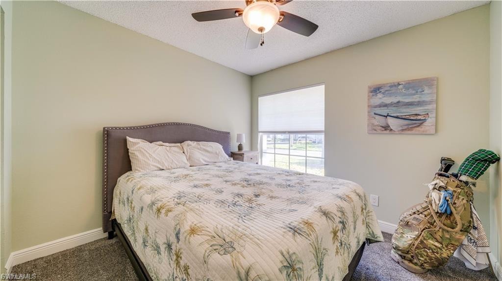 Bedroom with a textured ceiling, carpet floors, and a ceiling fan