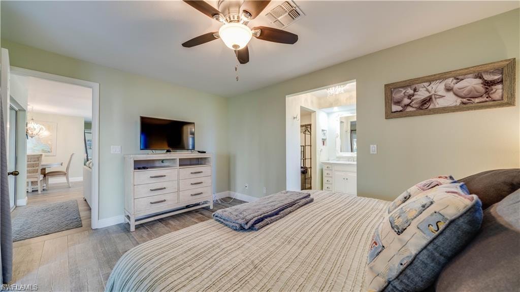 Bedroom with light wood-type flooring, a ceiling fan, and ensuite bath