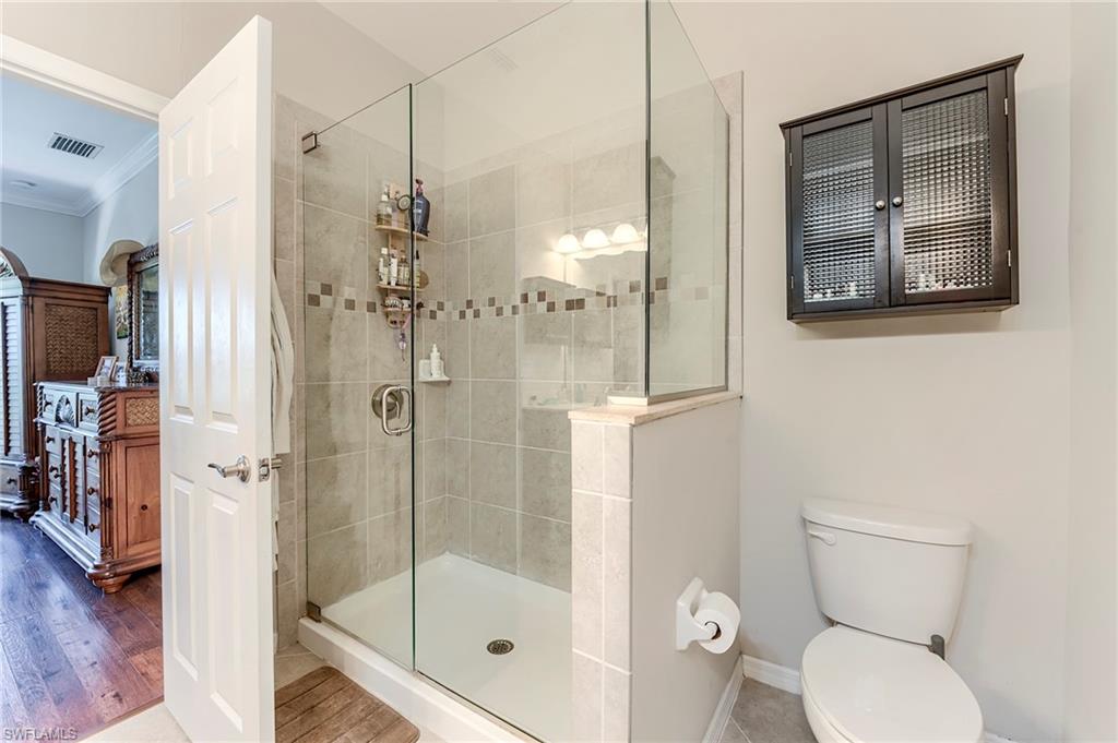 Full bathroom with crown molding, a stall shower, and wood finished floors