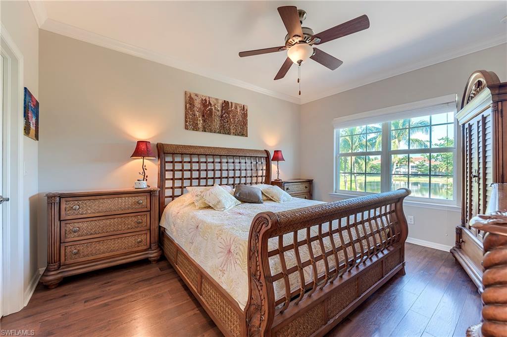 Bedroom with ornamental molding, dark wood-style floors, and ceiling fan