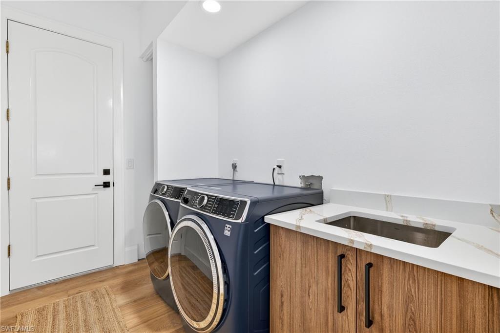 Laundry room with wood finished floors, independent washer and dryer, and recessed lighting