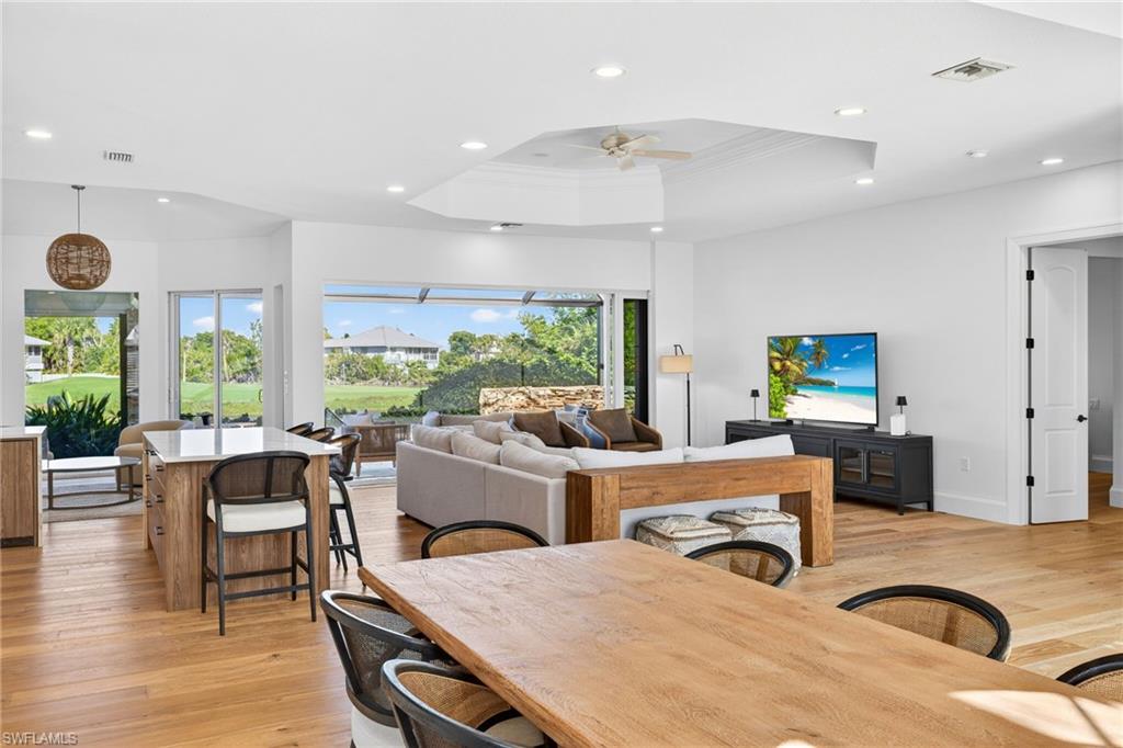 Dining space featuring light wood-style flooring, ceiling fan, a raised ceiling, recessed lighting, and ornamental molding
