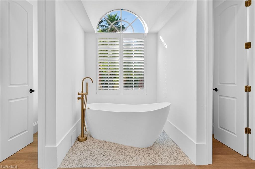 Full bathroom with a soaking tub and baseboards