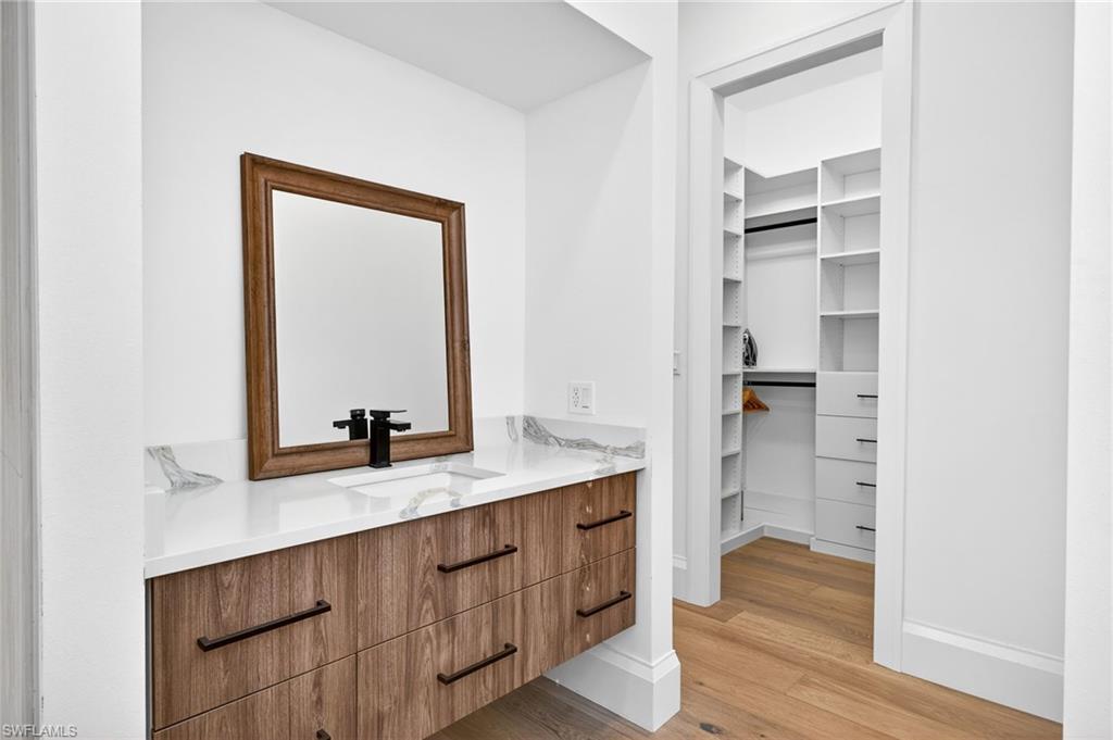 Bathroom with vanity, light wood-style floors, and a walk in closet
