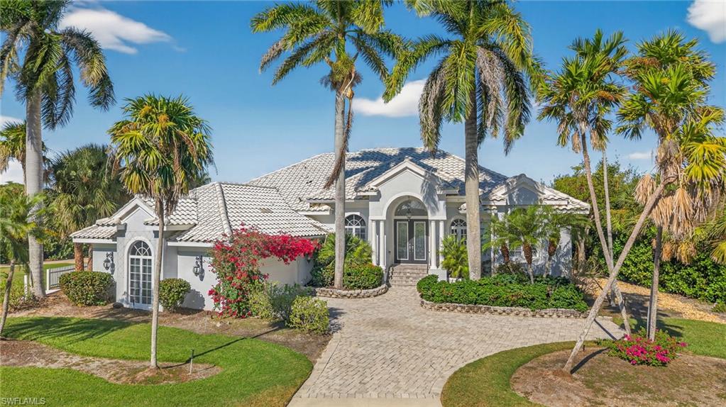 Mediterranean / spanish-style home with french doors, stucco siding, a tiled roof, and decorative driveway