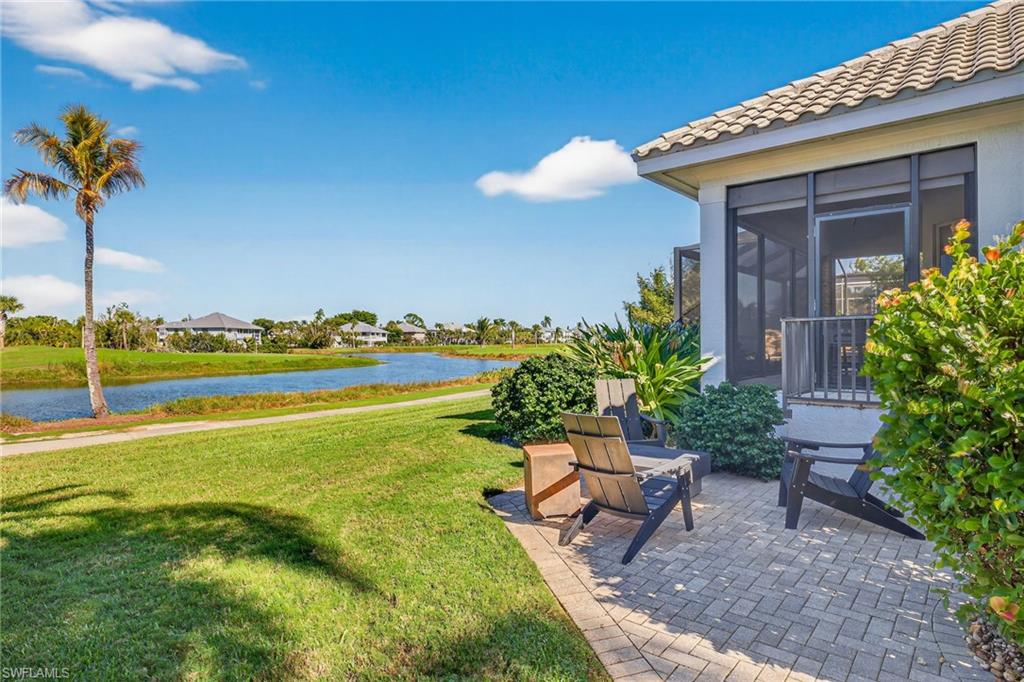 View of grassy yard featuring a water view, a patio, and a sunroom