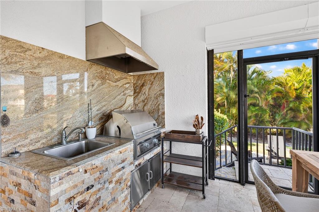 Kitchen with stone tile flooring, backsplash, wall chimney exhaust hood, and a textured wall
