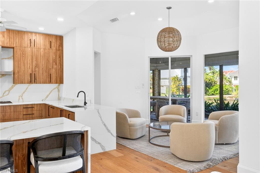 Kitchen featuring brown cabinets, light wood-type flooring, a kitchen bar, light stone countertops, and modern cabinets
