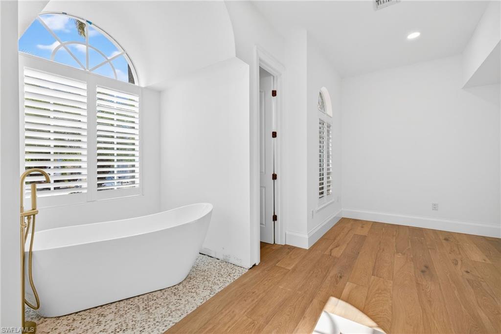 Full bathroom featuring a freestanding tub and light wood-type flooring