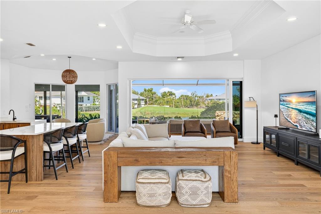 Living area with plenty of natural light, ornamental molding, light wood finished floors, ceiling fan, and recessed lighting