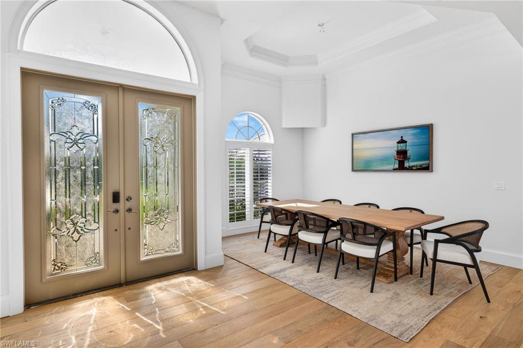 Entrance foyer featuring french doors, crown molding, a raised ceiling, and light wood-style floors