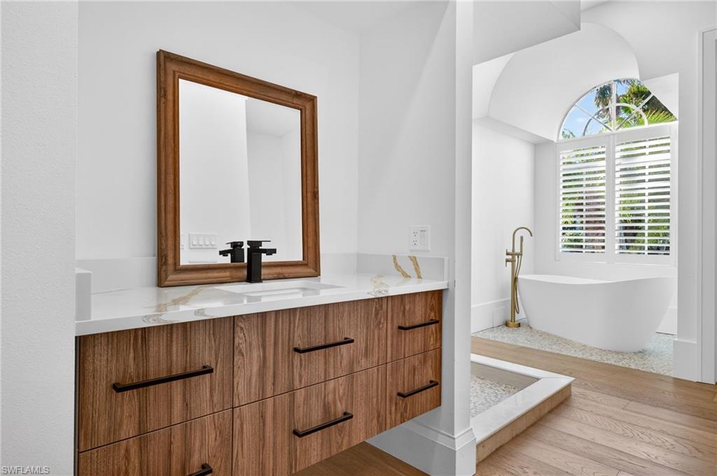 Full bathroom with vanity, a freestanding tub, and light wood-type flooring
