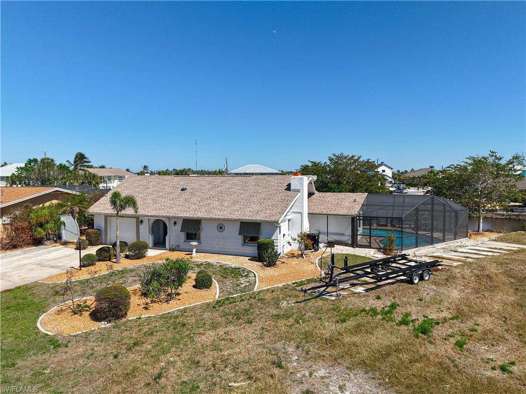 View of front of house featuring glass enclosure, a front lawn, concrete driveway, and an outdoor pool
